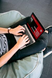 Person working remotely on a laptop while sitting comfortably on a beanbag chair indoors.